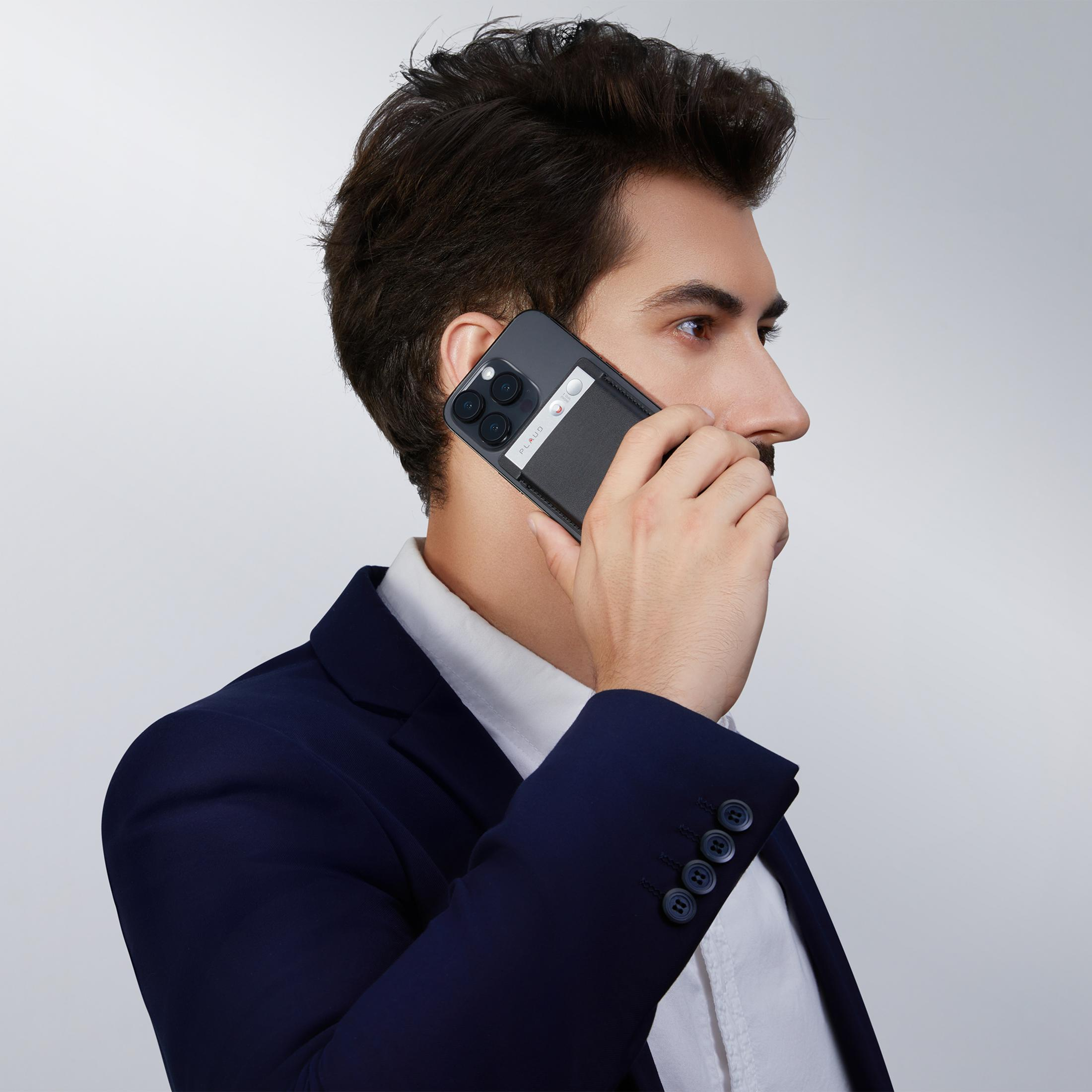 Mężczyzna w garniturze rozmawia przez telefon z etui na karty.