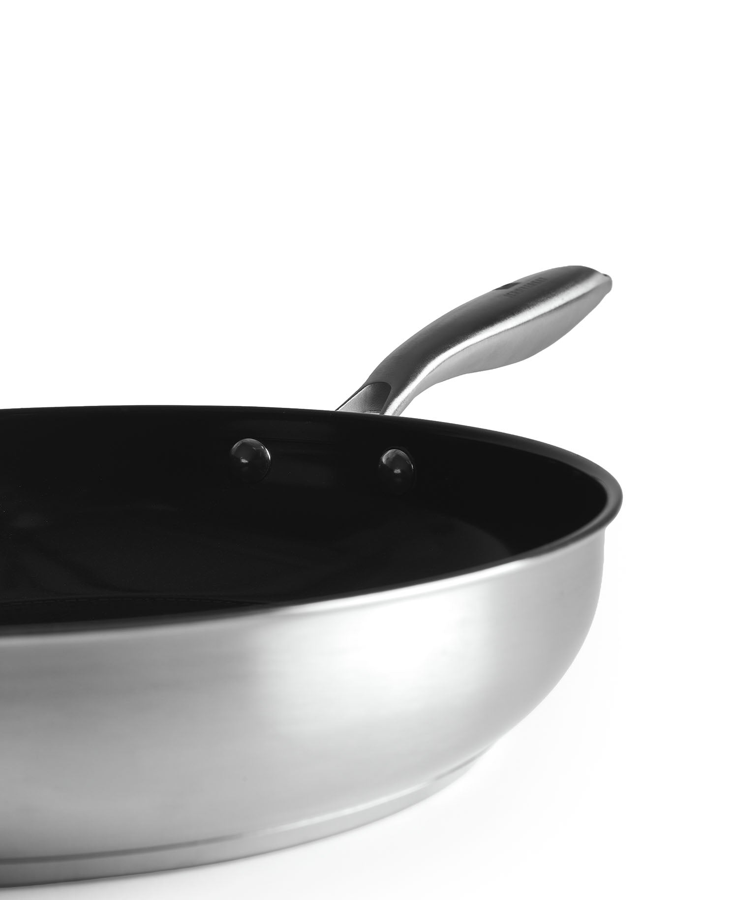 Primer plano de una sartén plateada con interior y mango negros.