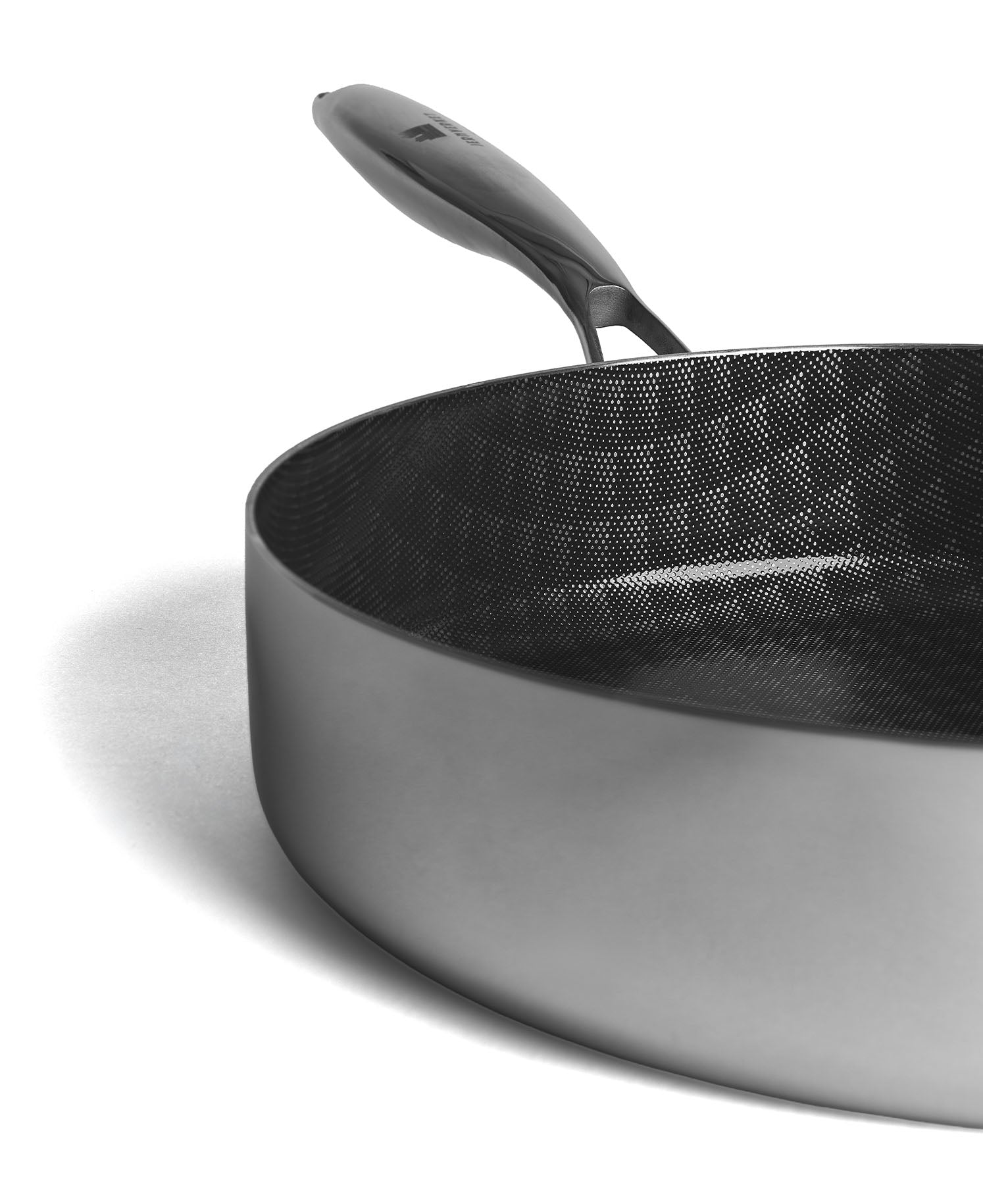 Primer plano de una sartén gris con interior negro texturizado y mango.
