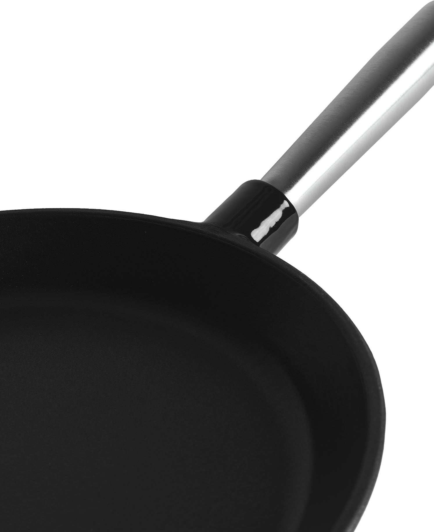 Primer plano de una sartén negra con mango plateado sobre fondo blanco.