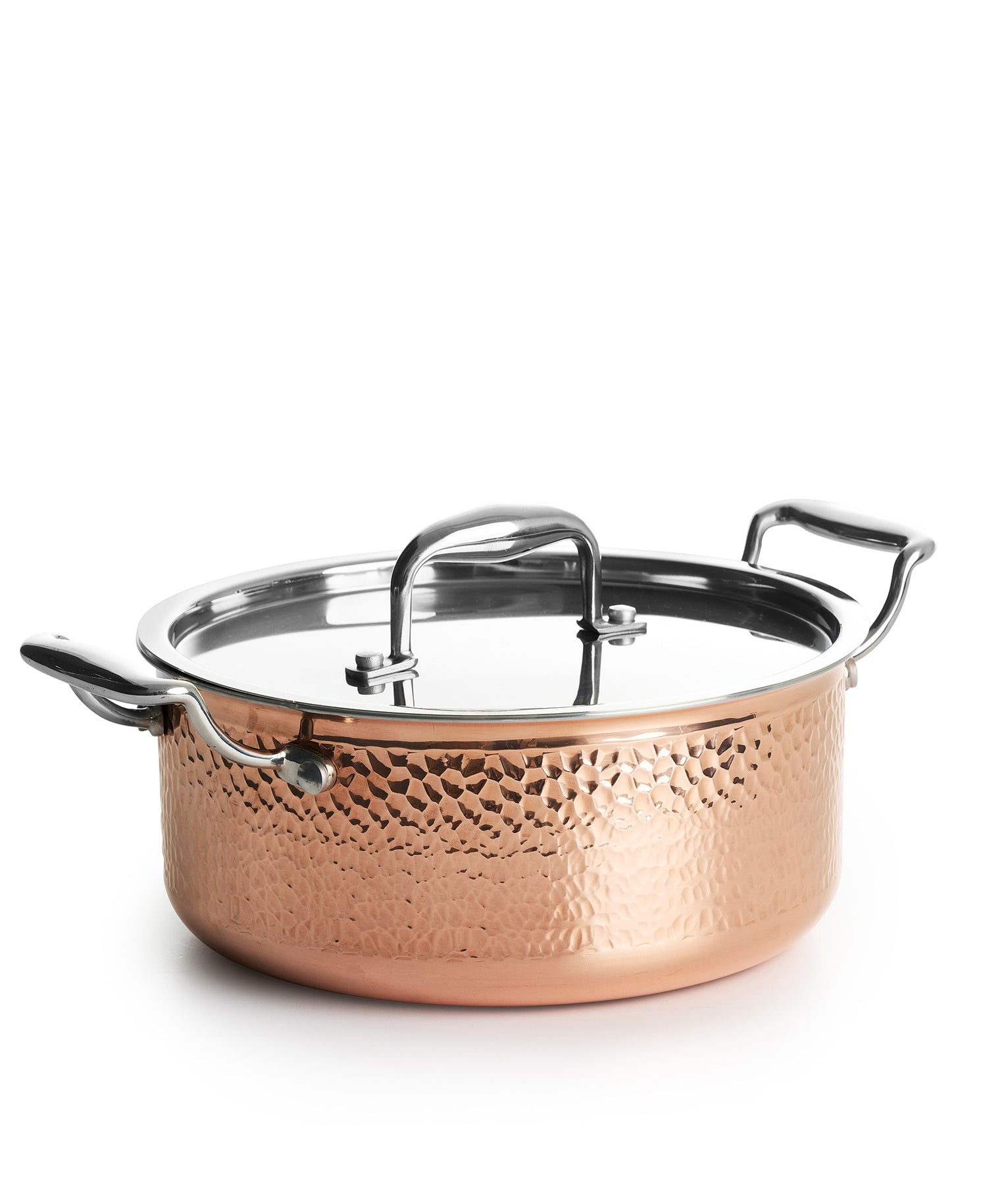 Una olla de cobre martillado con asas plateadas sobre fondo blanco.
