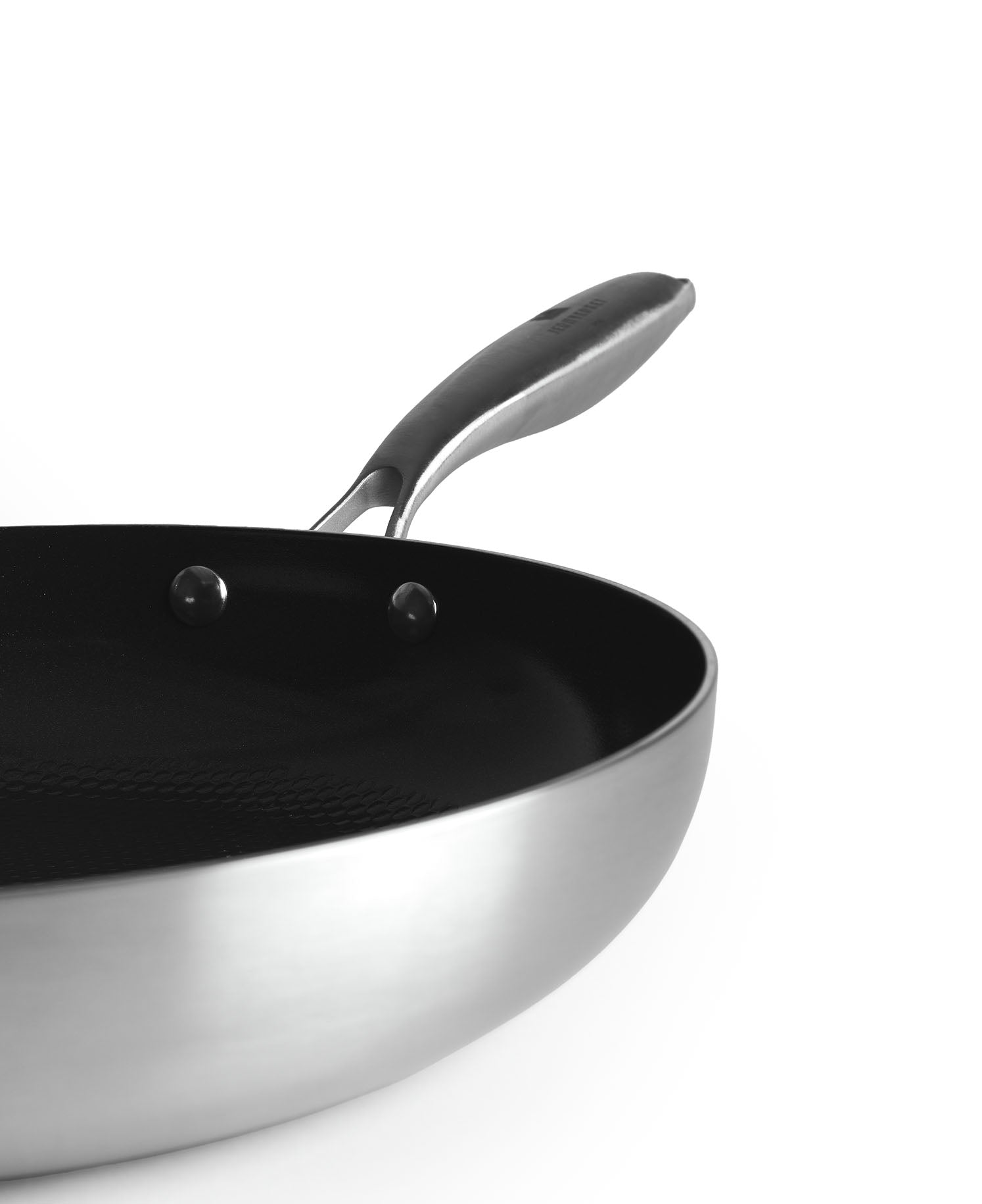 Una sartén plateada con interior y mango negros, sobre fondo blanco.