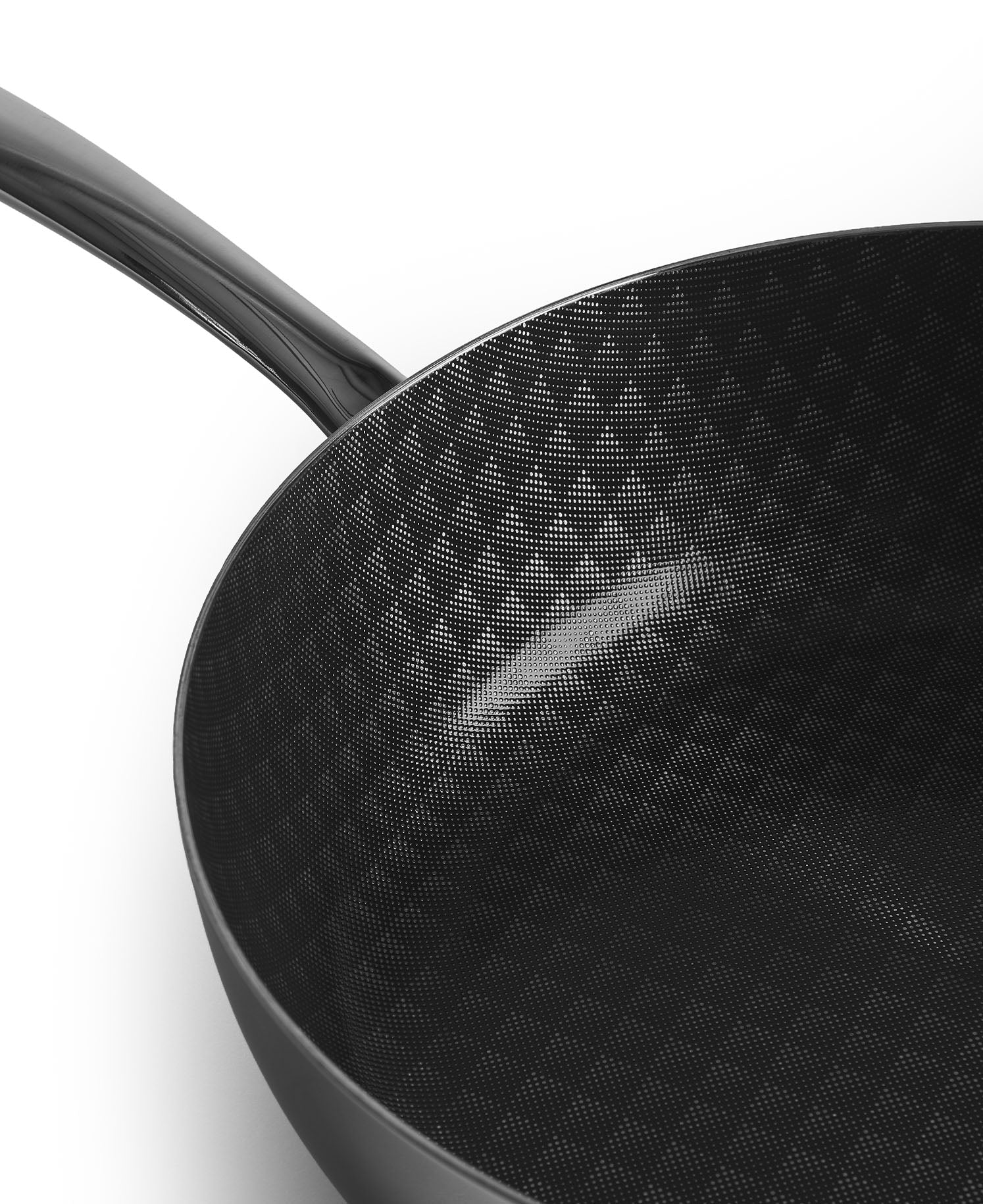 Sartén negra con superficie estampada sobre fondo blanco, primer plano.