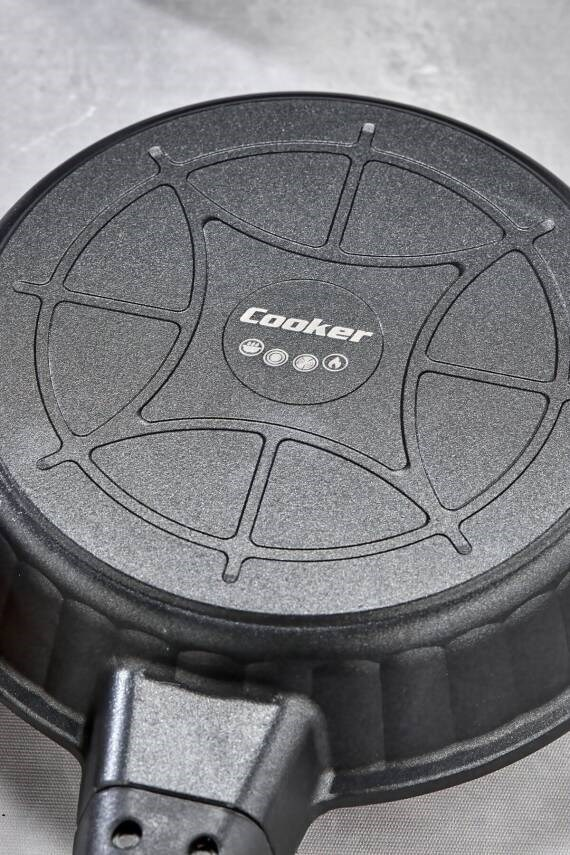 Üzerinde "Cooker" logosu ve pişirme sembolleri bulunan siyah bir tava altı.
