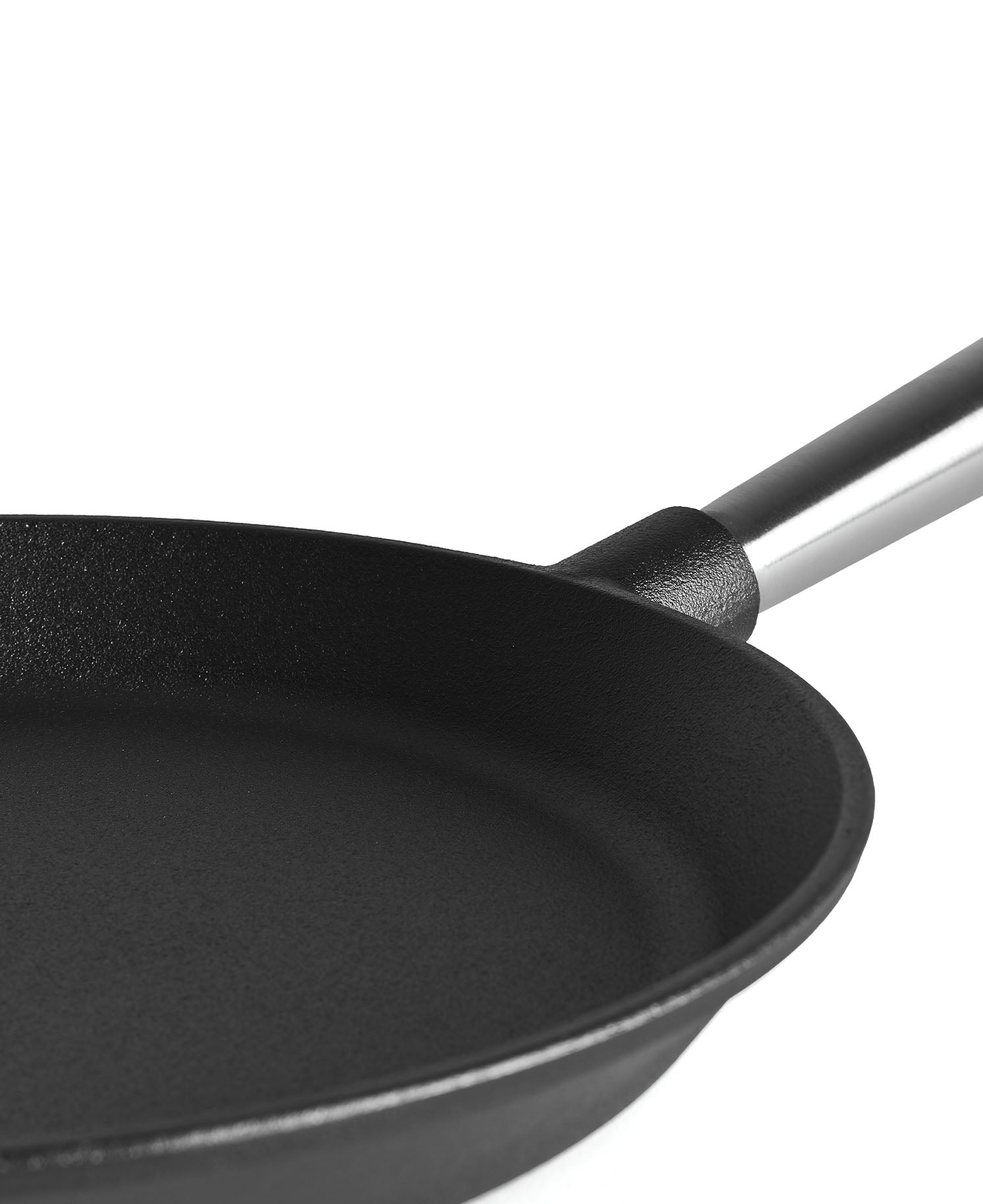 Primer plano de una sartén negra con mango plateado sobre fondo blanco.