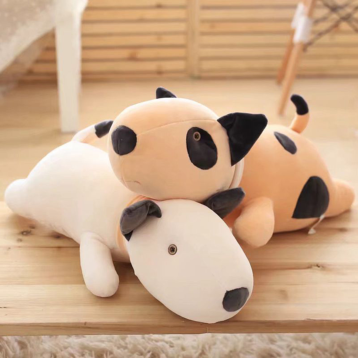 Due peluche cane giacciono su una superficie di legno, uno bianco, uno beige.