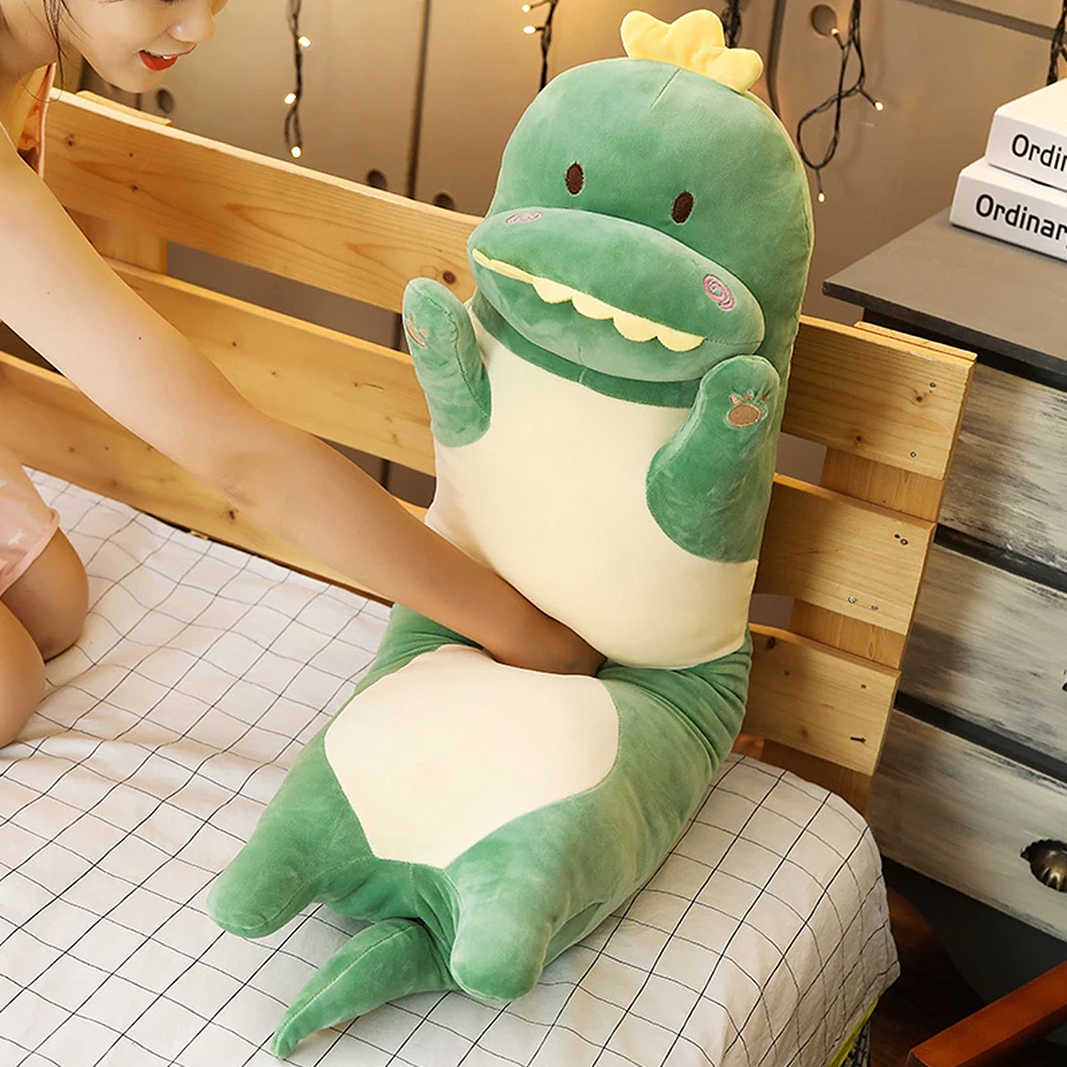 Un peluche di dinosauro verde giace su un letto, una donna lo accarezza.