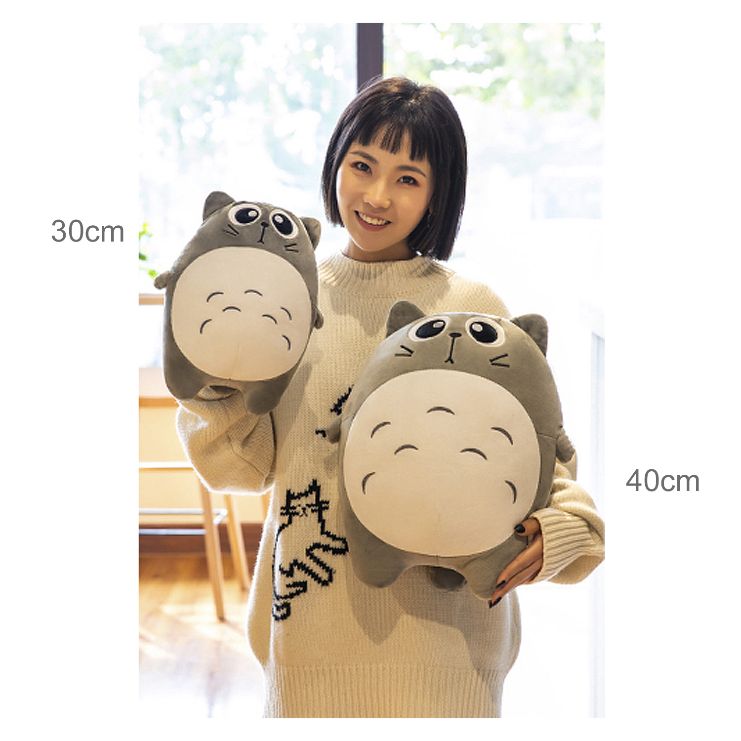 Una donna tiene due peluche grigi a forma di personaggi dei cartoni animati.