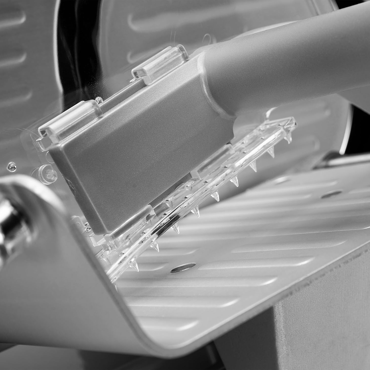 Primo piano di un'affettatrice con denti affilati e carrello metallico.
