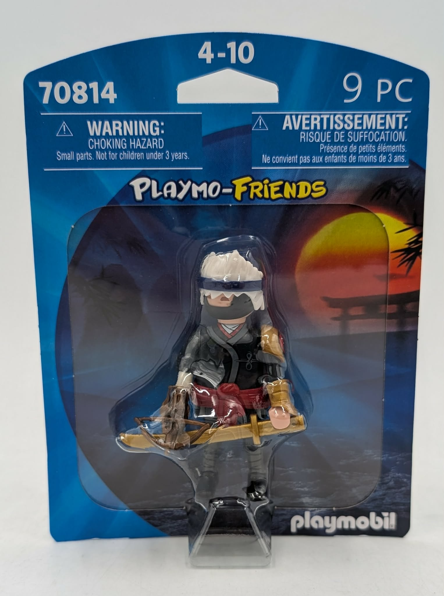 Personaggio Playmobil ninja con balestra in confezione, con sfondo al tramonto.