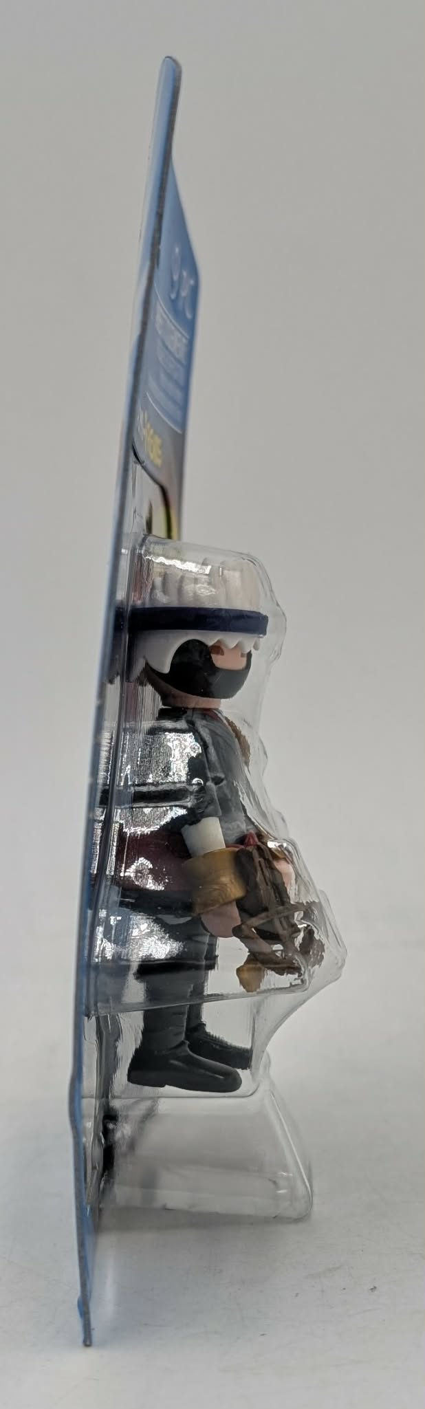 Personaggio giocattolo con abiti, maschera e cappello neri, in confezione blister.