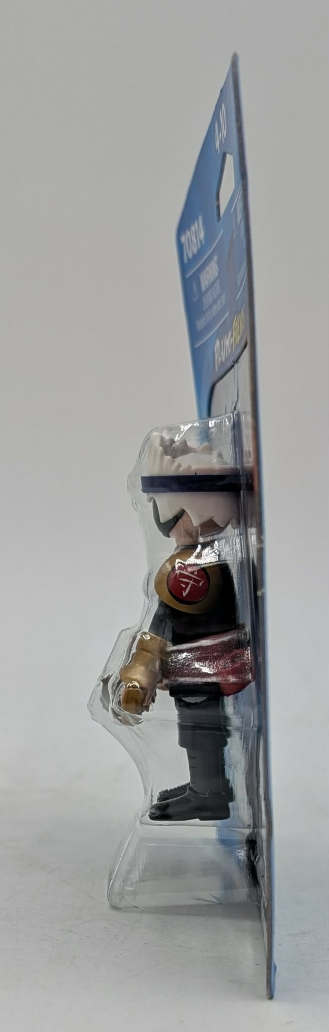 Action figure giocattolo in confezione con sfondo blu ed etichette di avvertenza.