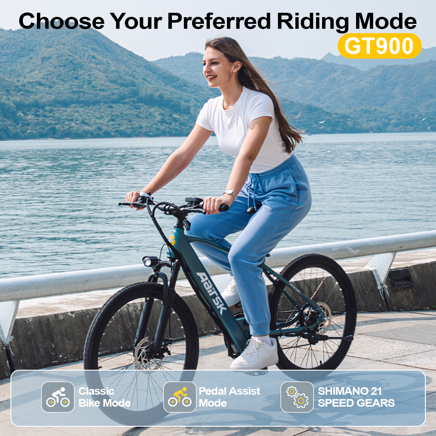 Donna in sella a una e-bike GT900 vicino all'acqua con montagne dietro.