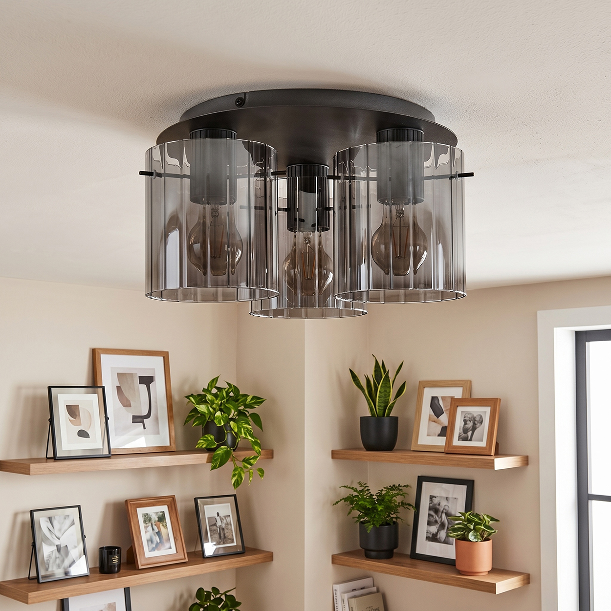 Eine moderne Deckenleuchte mit Glasschirmen hängt über Holzregalen mit Pflanzen und gerahmten Bildern.
