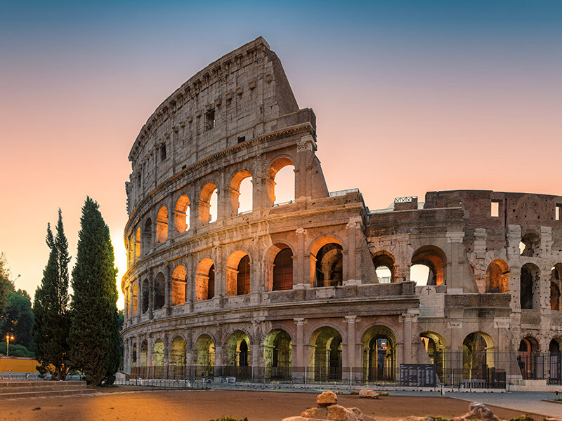 El Coliseo de Roma al atardecer, con luz cálida iluminando sus arcos y su antigua estructura de piedra.