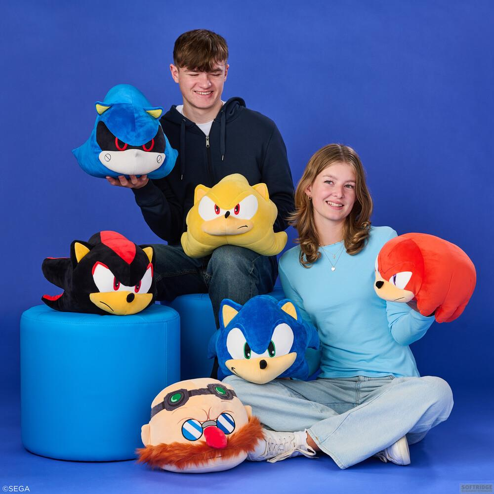 Due adolescenti seduti con peluche di Sonic su sfondo blu.