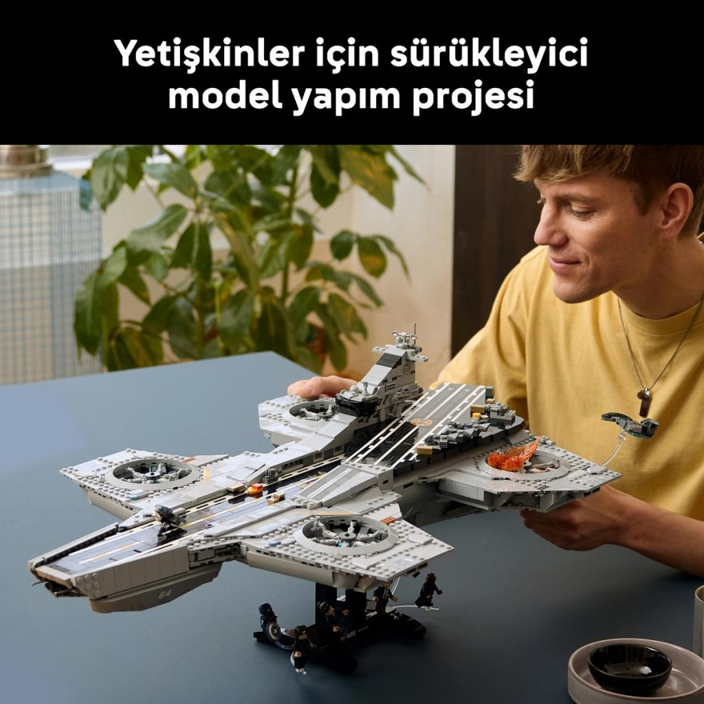 Un uomo guarda una nave Lego grigia dettagliata con fiamme arancioni.
