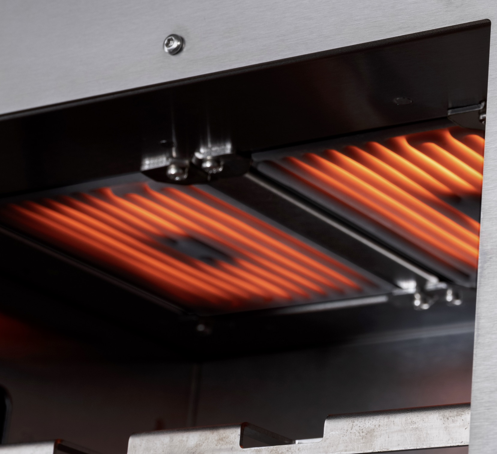 Glühende rote Heizelemente unter einem Grillrost in einem Metallgehäuse.