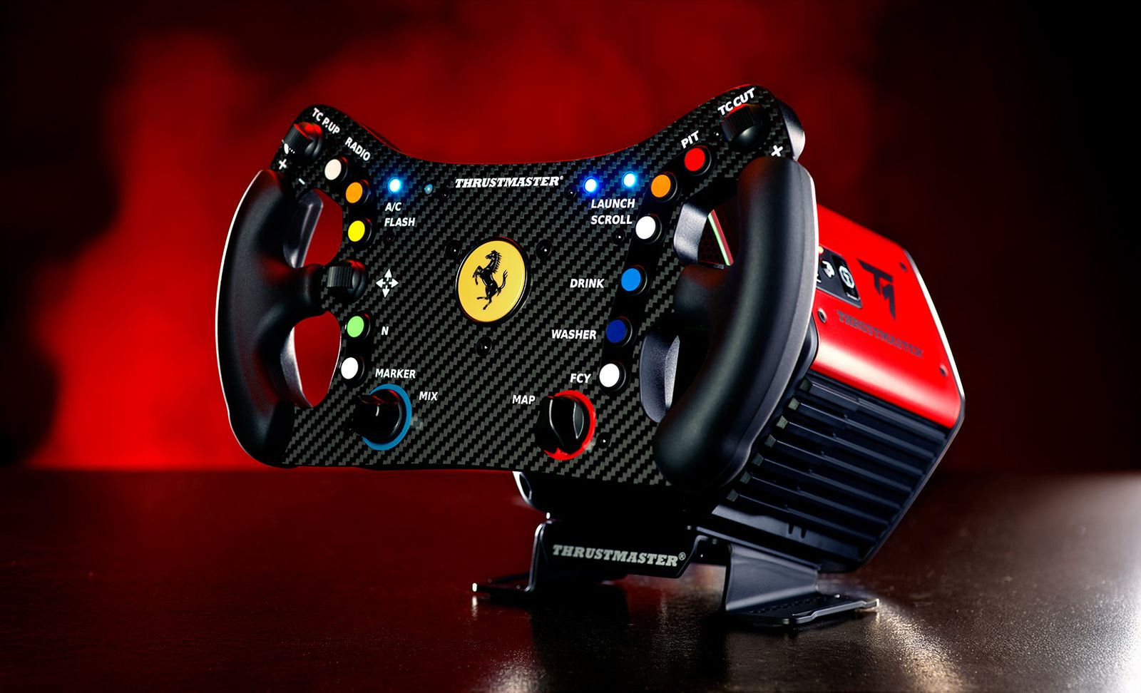 Un volante da corsa nero con logo Ferrari e pulsanti, accanto a un'unità rossa.