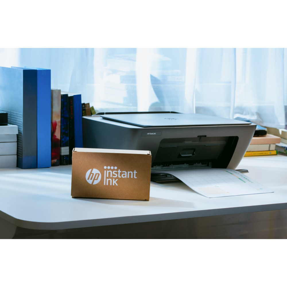 Drukarka HP z pudełkiem HP Instant Ink obok na biurku.