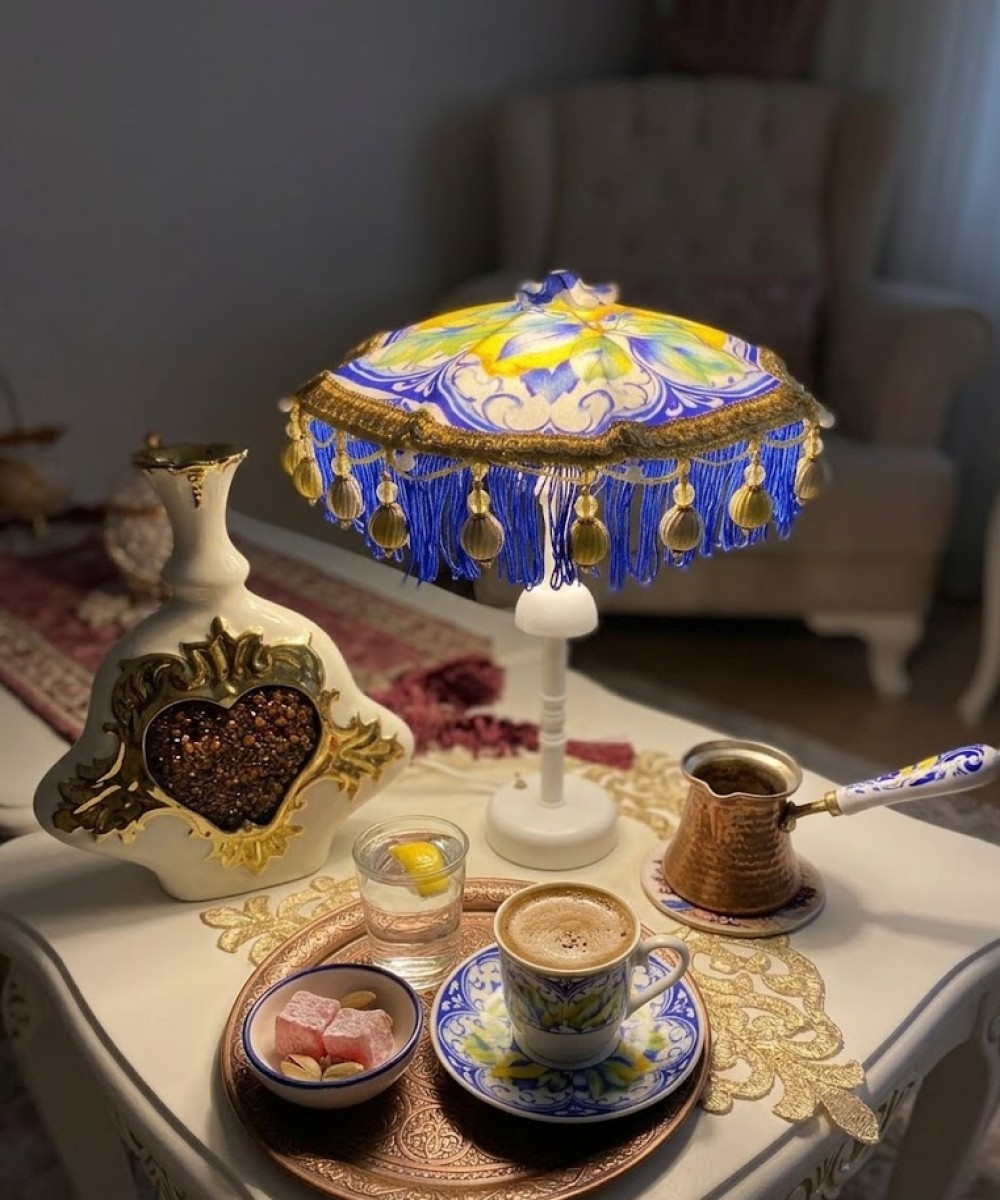 Türk kahvesi, su, tatlı ve lamba bulunan bir masa.