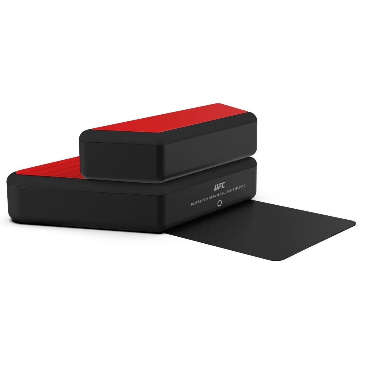 Dos cajas negras UFC con tapas rojas apiladas sobre una superficie negra.