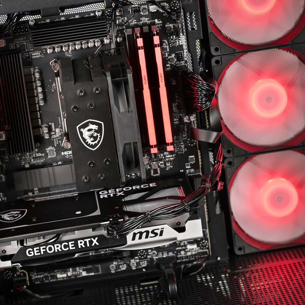 Primo piano di una scheda madre di computer con RAM rossa luminosa, dissipatore CPU e ventole.