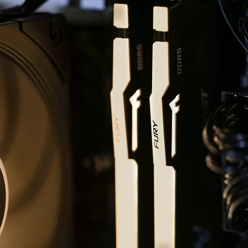Dwa białe moduły RAM DDR5 z napisem „FURY” wewnątrz komputera.