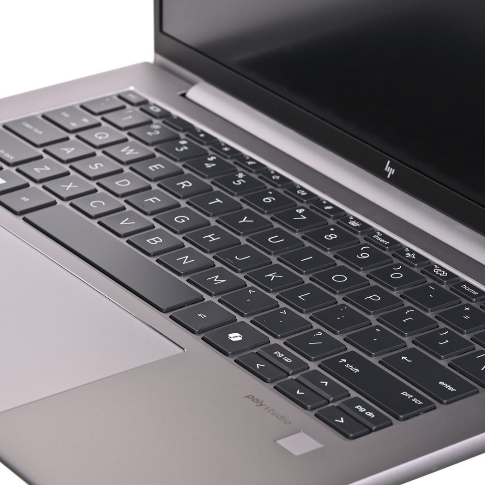 Zbliżenie srebrnej klawiatury i gładzika laptopa z widocznym ekranem.