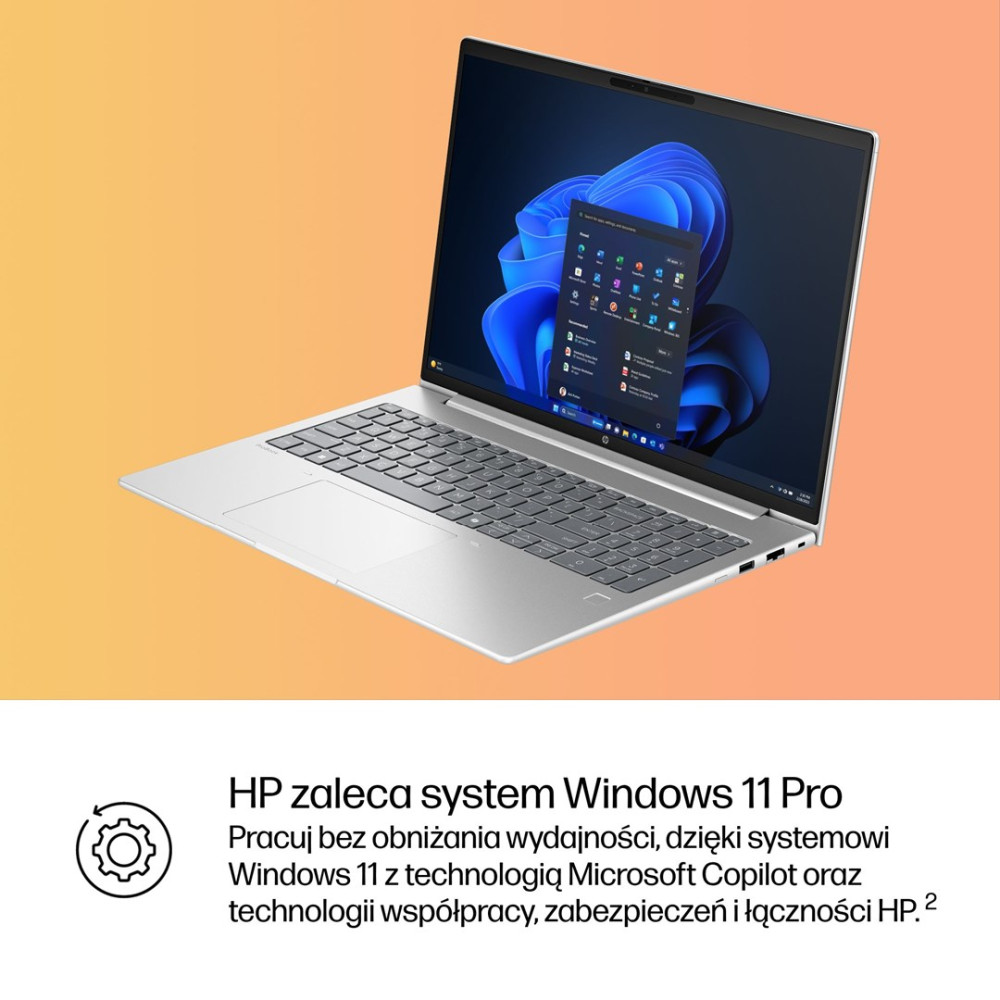 Srebrny laptop z systemem Windows 11 na ekranie, na pomarańczowym tle.