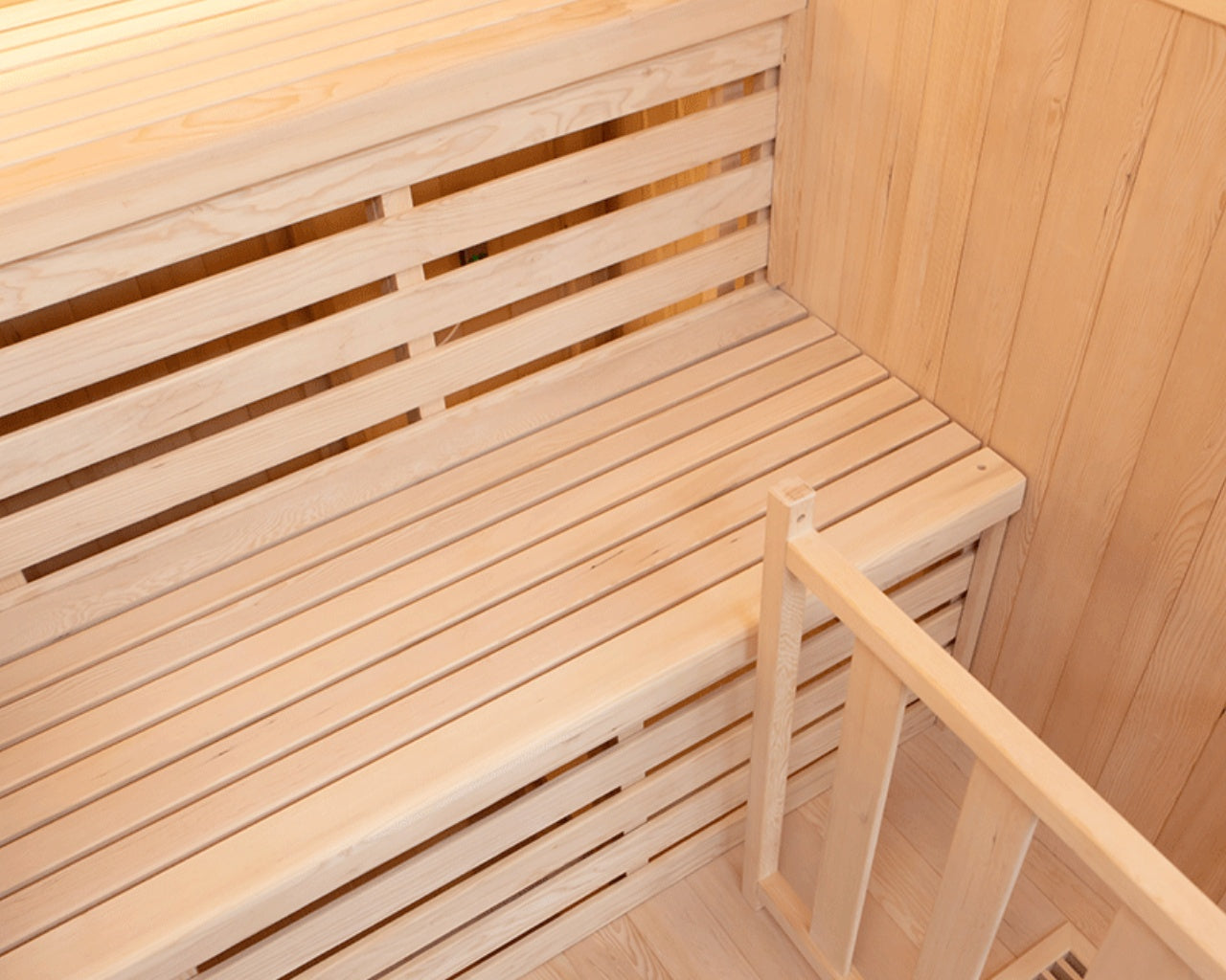 Bancos de madera en una sauna con listones horizontales y una pequeña barandilla.