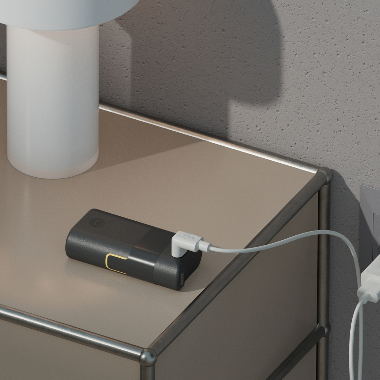 Czarna powerbank z białym kablem ładuje się z gniazdka ściennego.