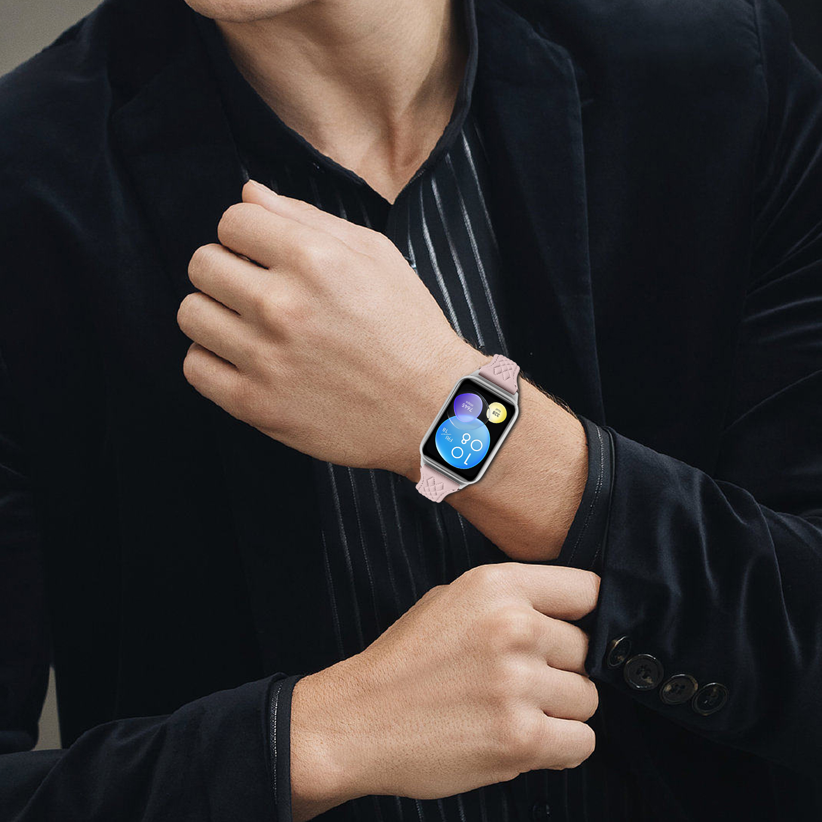 Mann in schwarzem Sakko mit rosa Smartwatch, die 10:08 Uhr anzeigt.