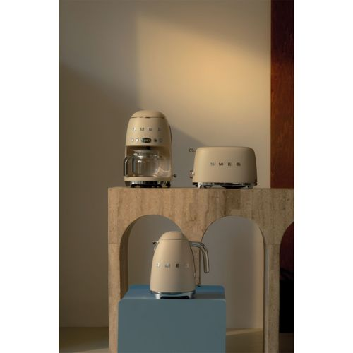 Drei cremefarbene SMEG-Küchengeräte: Kaffeemaschine, Toaster und Wasserkocher.