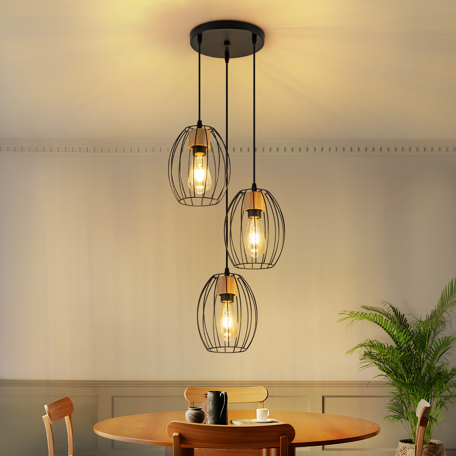 Hängende Lampe mit drei Käfigschirmen über einem Holztisch mit Pflanzen.