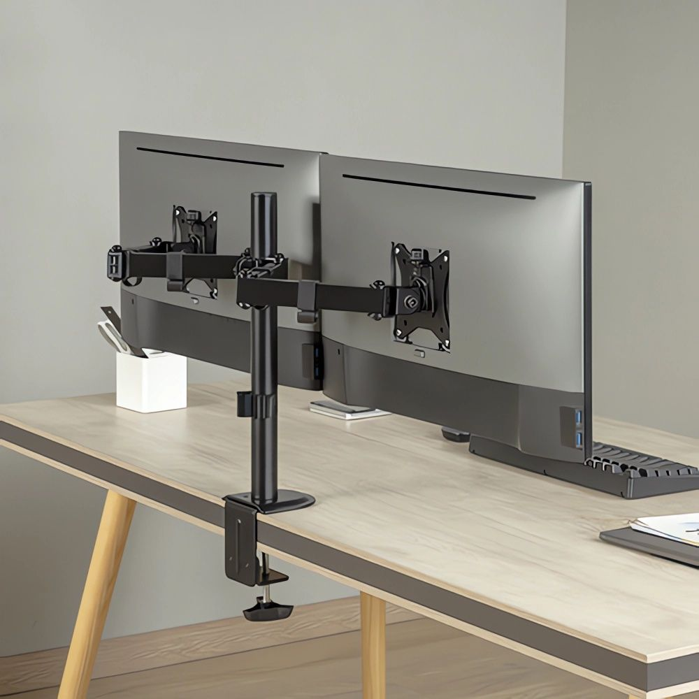 Schwarzer Doppelmonitorarm auf einem Schreibtisch mit zwei Monitoren und einer Tastatur.