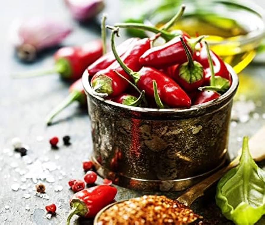 Peperoncini rossi in una ciotola con spezie ed erbe aromatiche vicine.