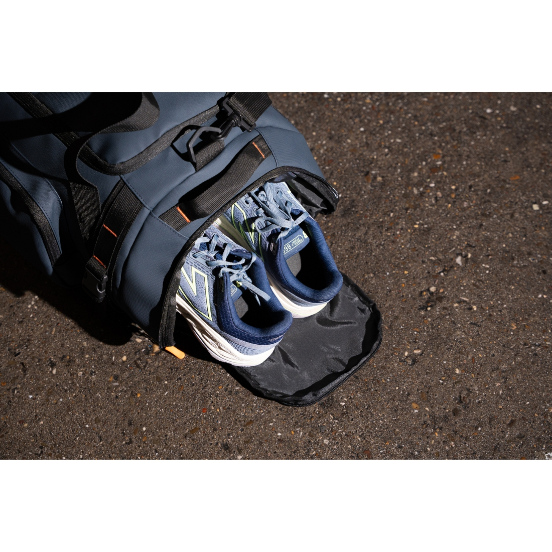 Ein blauer Sportbeutel mit blauen Laufschuhen darin, auf Asphalt.