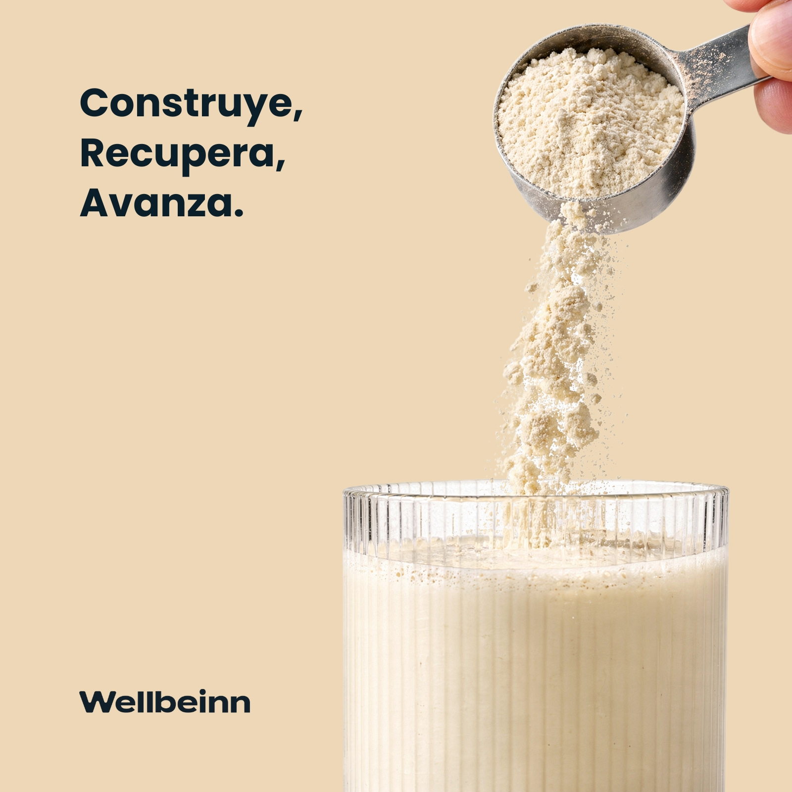 Una cuchara medidora de polvo se vierte en un vaso con líquido cremoso.