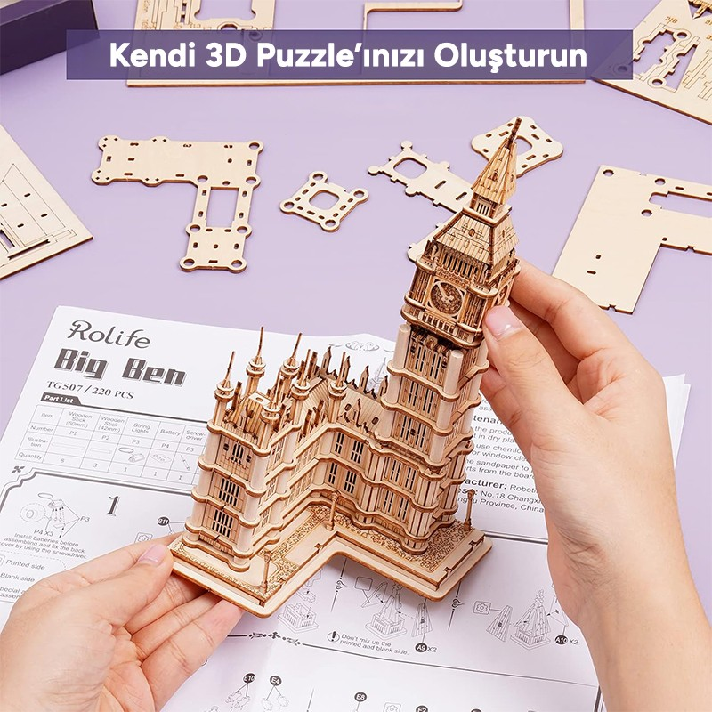 Una persona assembla un puzzle 3D in legno del Big Ben, con pezzi e istruzioni visibili.