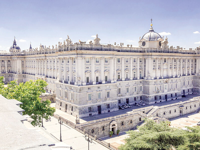 Un edificio grande y claro con cúpula y muchas ventanas, árboles cerca.