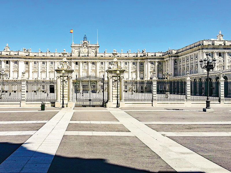 Un gran edificio blanco con una valla delante en un día soleado.
