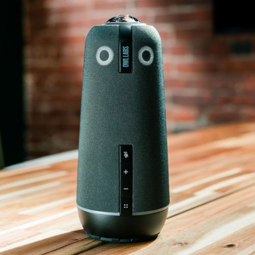 Un altoparlante grigio con logo Owl Labs su un tavolo di legno.