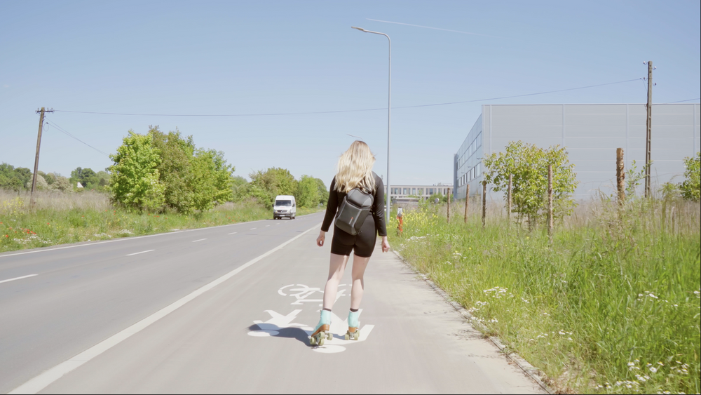 Kobieta w blond włosy jeździ na rolkach po ścieżce rowerowej obok drogi.