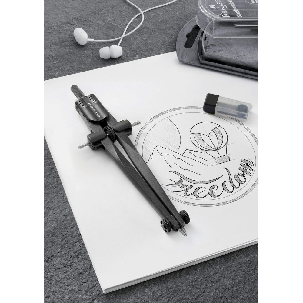 Un compás de dibujo sobre papel con un boceto de globo aerostático y la palabra "Freedom".