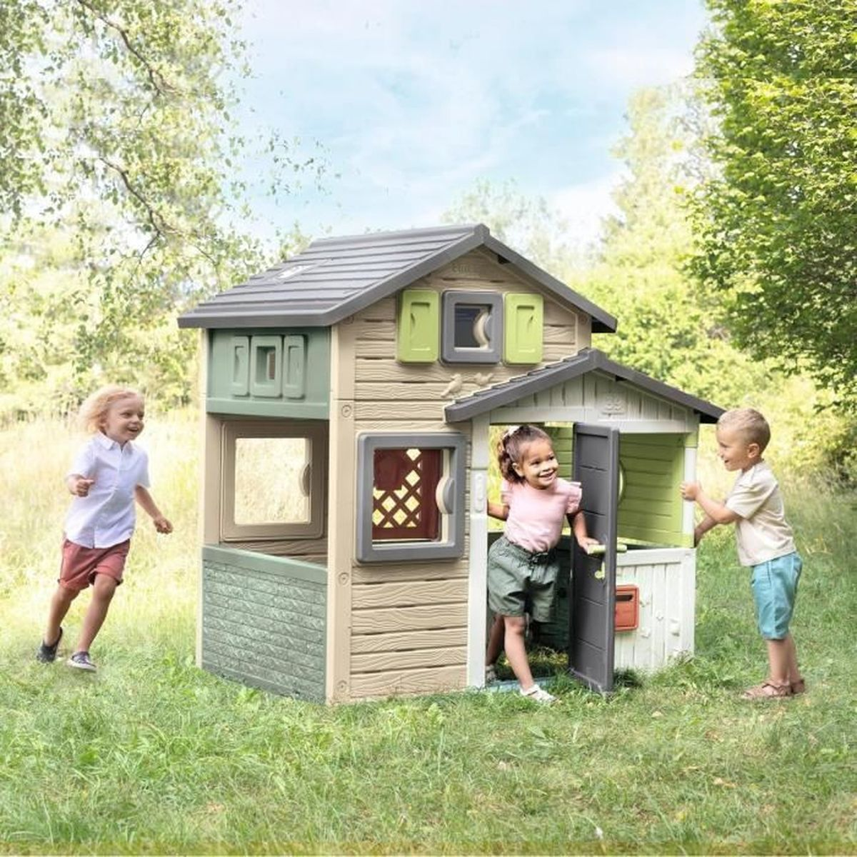 Tre bambini giocano davanti e dentro una casa gioco colorata in giardino.