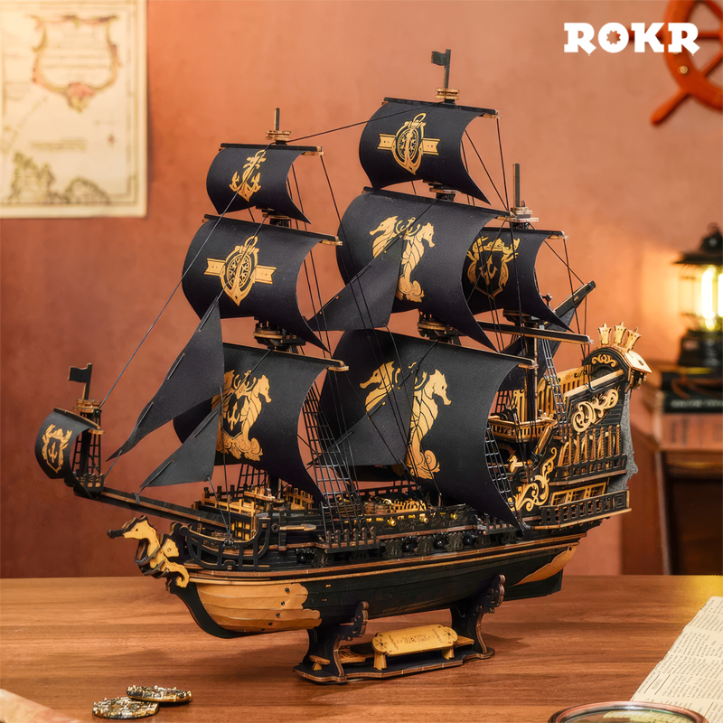 Modèle détaillé d'un galion noir avec garniture dorée, quatre mâts et voiles noires.