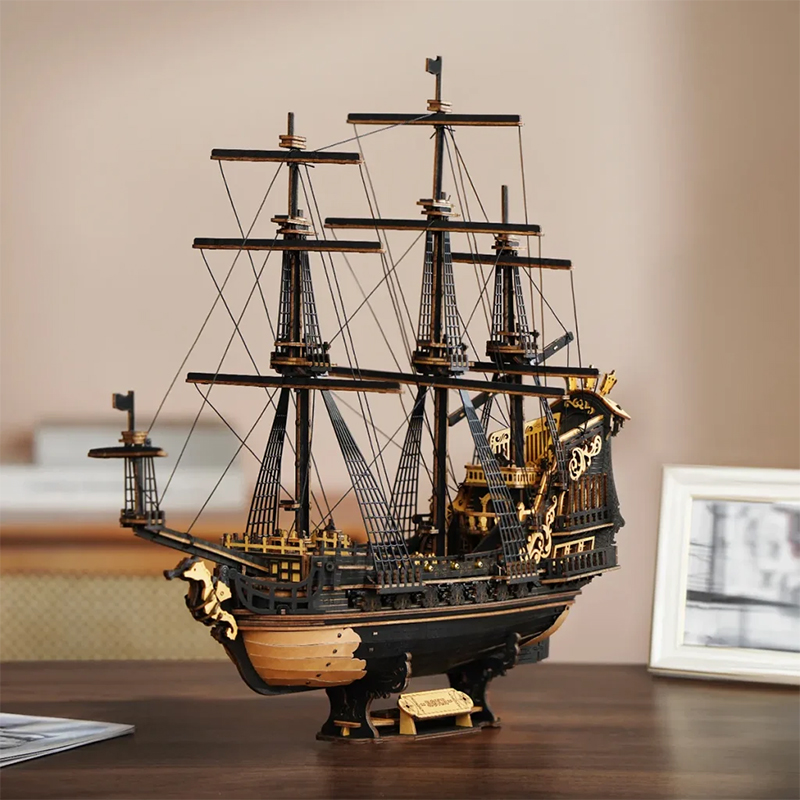 Modèle détaillé en bois d'un navire pirate noir et or avec voiles et gréement.