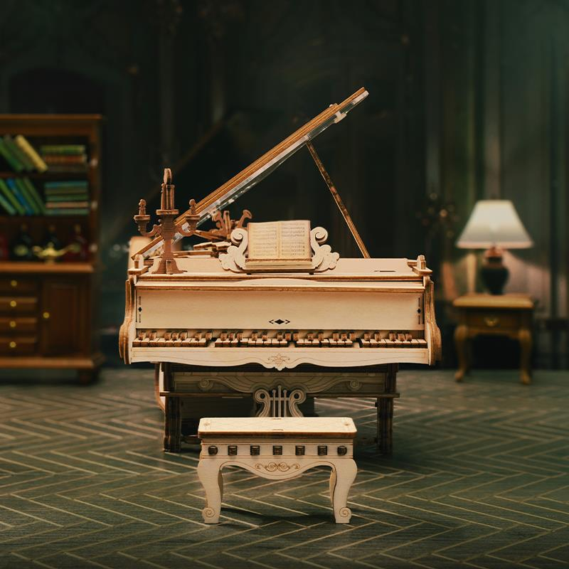 Un piano à queue miniature en bois avec partition et tabouret, devant une bibliothèque.