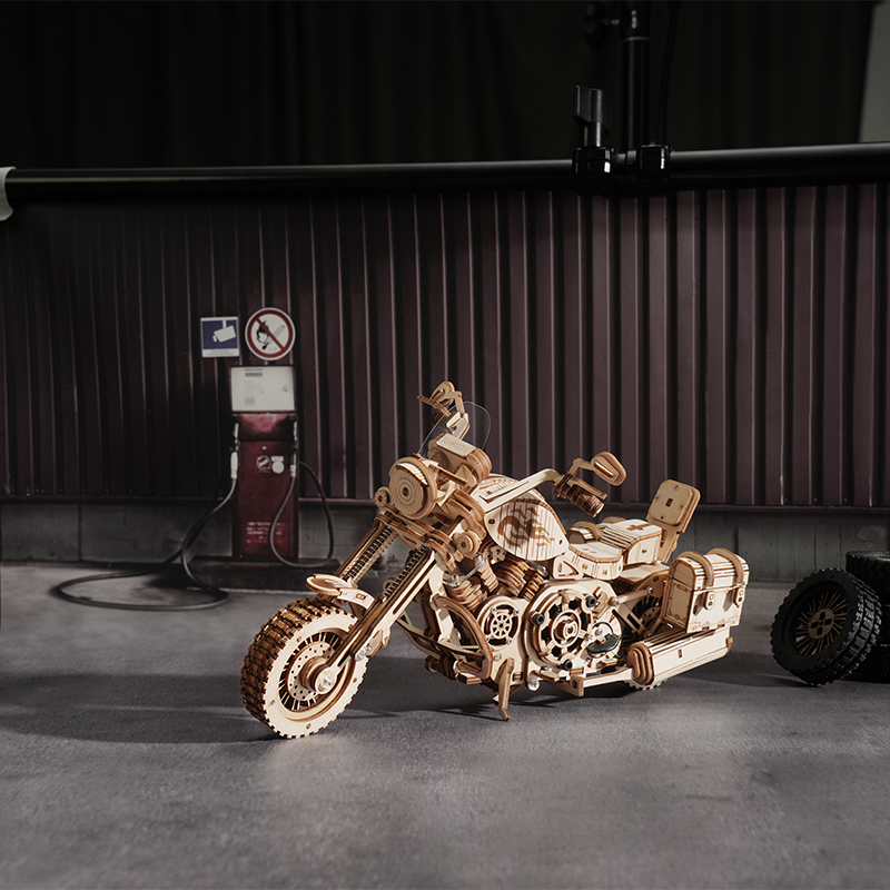 Benzin pompası olan bir garaj kapısının önünde ahşap motosiklet modeli.